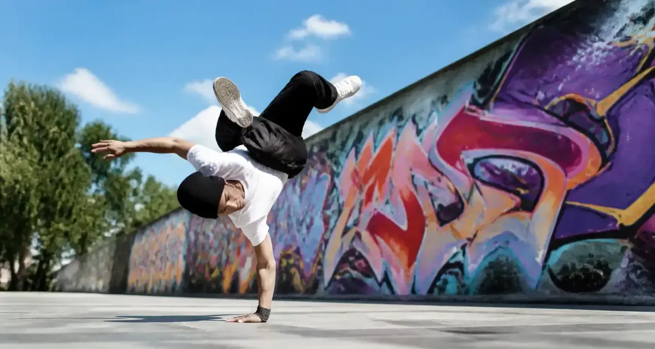 Danseur de breakdance sur une place publique devant un mur graffé