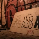 Abcs in graffiti sur planche lettres A B C devant mur de briques